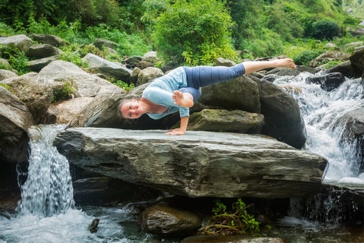Young fit woman doing yoga oudoors at waterfall photo