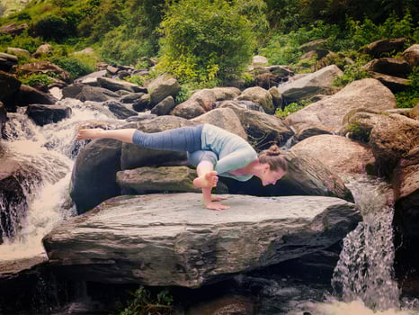 Young sporty fit woman doing yoga oudoors at tropical waterfall photo