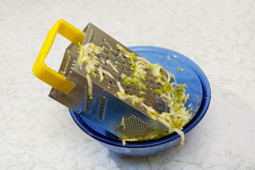 zucchini in a bowl, grated on a vegetable grater photo