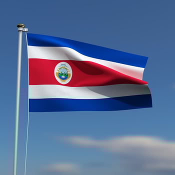 Costa Rica Flag is waving in front of a blue sky with blurred clouds in the background photo