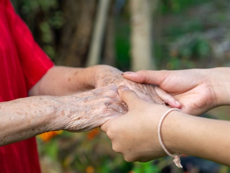Close-up of a young woman's hands holding an elderly female's hands. Concept of aged people and healthcare photo