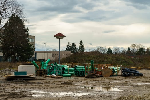 Dirty construction site after rain with a bunch of plastic green pipes. photo