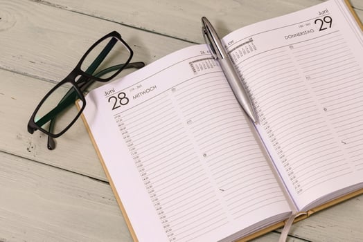 Lying on the table, an open schedule - planner with an auto pen and glasses nearby. photo