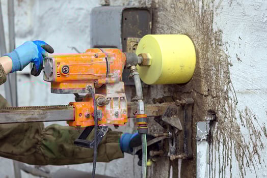 Worker using an electric drill to make a hole in a concrete wall, closeup photo