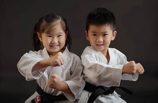 A boy and a girl, both dressed in martial arts uniforms, practice Taekwondo, Aikido, or Jujitsu. . photo