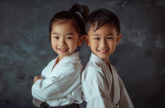 A boy and a girl, both dressed in martial arts uniforms, practice Taekwondo, Aikido, or Jujitsu. . photo