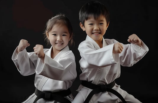 A boy and a girl, both dressed in martial arts uniforms, practice Taekwondo, Aikido, or Jujitsu. . photo