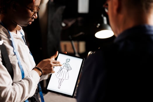 Creative skilled fashion designer showing atelier shop manager graphic design sketch drawing of wedding dress she is working on. Apprentice and master manufacturing bespoke sartorial outfit photo