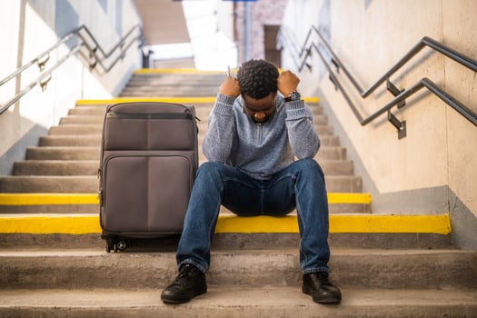Worried man with a phone and suitcase sitting on a stairs at the railway station. photo