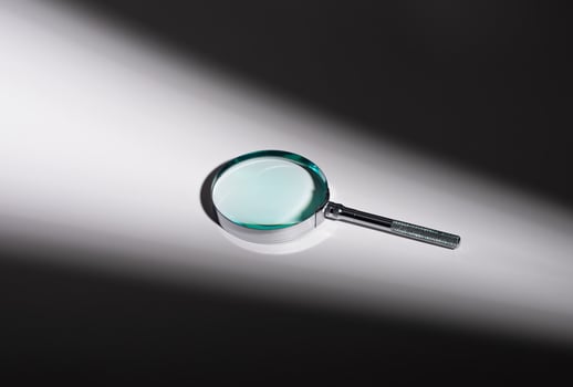 Silver magnifying glass on glass surface, shadow and light play. Optical zoom lens concept, photo