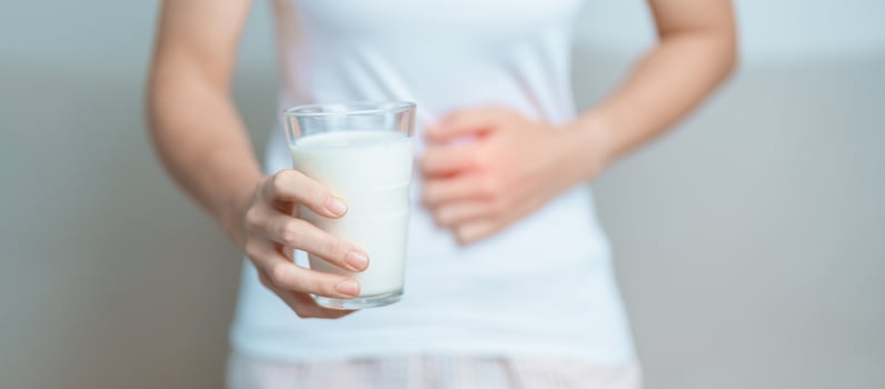 Lactose intolerance and Milk allergy concept. woman hold Milk glass and having abdominal cramps and pain when drink Cow Milk. Symptom stomach ache, Dairy intolerant, Nausea, Bloating, Gas and Diarrhea photo