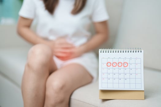 Menstruation period cycle of monthly and Stomachache concepts. woman having abdomen pain with calendar, illness female suffer from premenstrual ache and body Health problem on sofa at home photo
