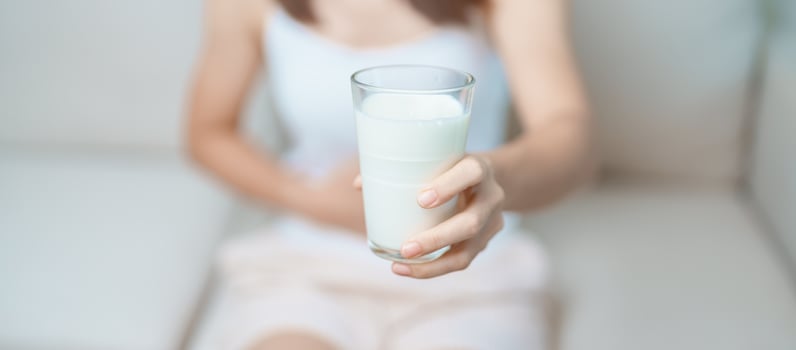 Lactose intolerance and Milk allergy concept. woman hold Milk glass and having abdominal cramps and pain when drink Cow Milk. Symptom stomach ache, Dairy intolerant, Nausea, Bloating, Gas and Diarrhea photo