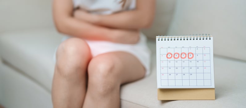 Menstruation period cycle of monthly and Stomachache concepts. woman having abdomen pain with calendar, illness female suffer from premenstrual ache and body Health problem on sofa at home photo