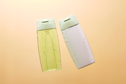 Shampoo and hair conditioner in water on a beige background. View from below. photo