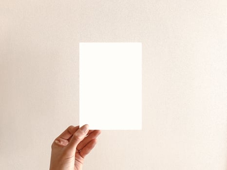 Hand Holding a Blank White Card Against a Neutral Background photo