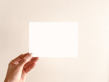 Hand Holding a Blank White Card Against a Neutral Background photo