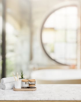 Bath accessories on a luxury white marble tabletop in contemporary luxurious bathroom with a bathtub photo