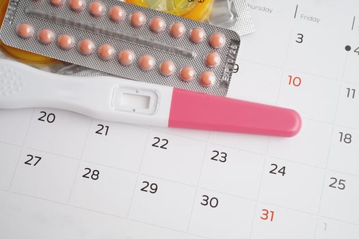 Pregnancy test with birth control pills and condom for female on calendar, ovulation day. photo