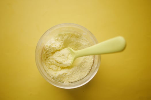 top view of baby milk powder and spoon on yellow background. photo