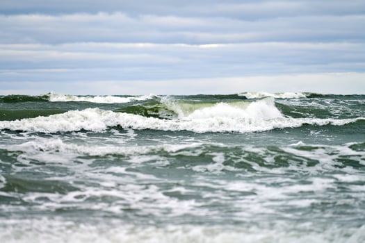 Blue sea with foaming waves and cloudy sky, seascape photo
