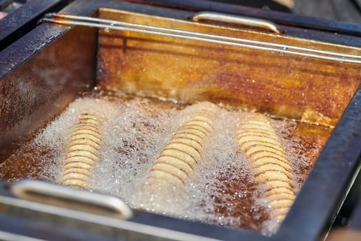 Cooking spiral fried potato in boiling oil, rich in fat and calories fast food, unhealthy delicious photo