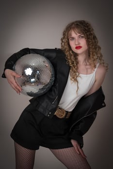 Confident woman dancer holds disco ball. Woman exudes an air of sensuality during nightclub party photo