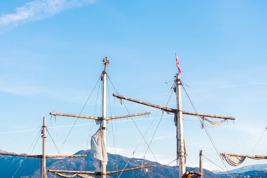 Ship masts against the background of blue sky and mountains. Masts against the backdrop of the Caucasus Mountains. photo