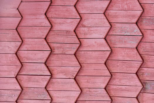 Painted red wooden boards laid in a herringbone ornament frieze as background, texture photo