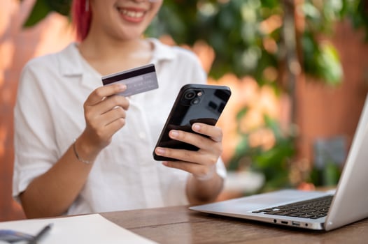 A woman holding a smartphone and a credit or debit card, making an online payment, shopping online. photo