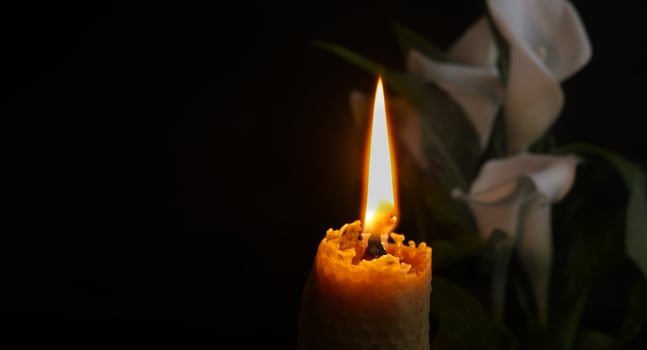 White calla lily flowers and burning wax candle in darkness photo