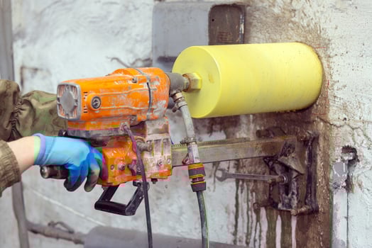 Worker using an electric drill to make a hole in a concrete wall, closeup photo