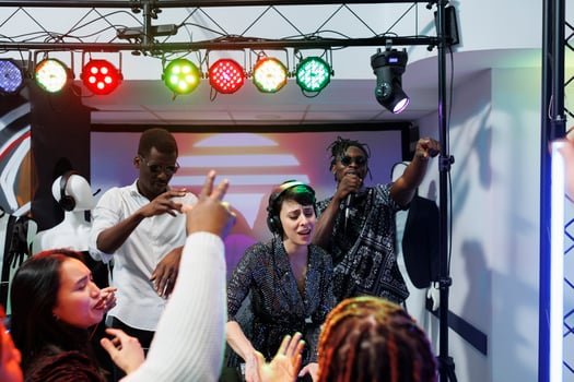 Group of diverse musicians playing on stage and engaging clubbers crowd to party in nightclub. Music band performing while young people dancing and cheering on dancefloor in club photo