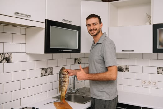 Man cutting fresh fish in kitchen in home. Man butchering fish for cook. photo