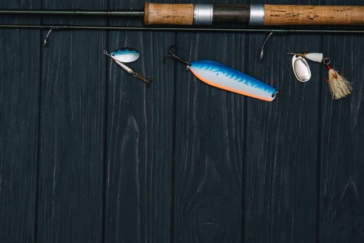Fishing tackle - fishing spinning, hooks and lures on darken wooden background. Top view. photo