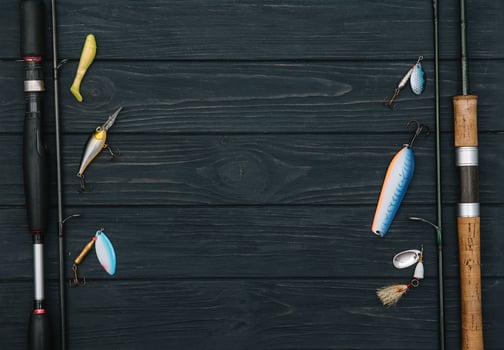 Fishing tackle - fishing spinning, hooks and lures on darken wooden background. Top view. photo