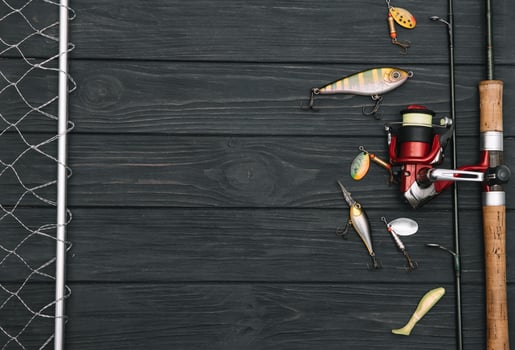 Fishing tackle - fishing spinning, hooks and lures on darken wooden background. Top view photo