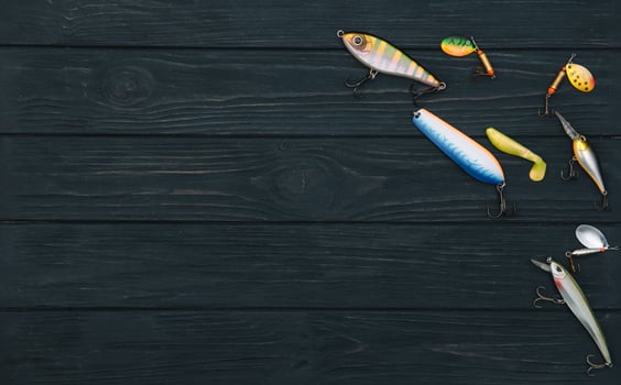 Fishing tackle - fishing spinning, hooks and lures on darken wooden background. Top view photo