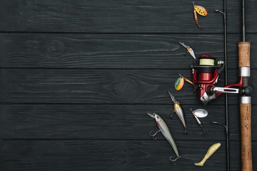 Fishing tackle - fishing spinning, hooks and lures on darken wooden background. Top view photo