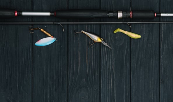 Fishing tackle - fishing spinning, hooks and lures on darken wooden background. Top view. photo