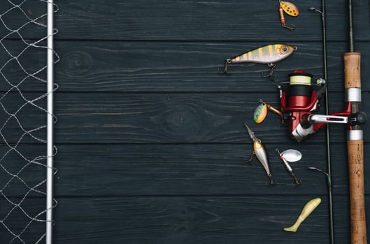 Fishing tackle - fishing spinning, hooks and lures on darken wooden background. Top view photo