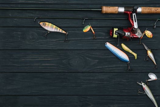Fishing tackle - fishing spinning, hooks and lures on darken wooden background. Top view photo