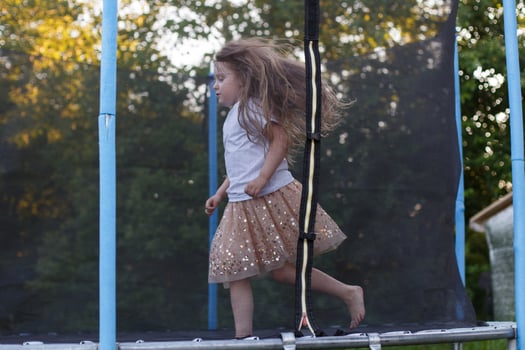 Little child girl jumping on the trampoline in the back yard photo