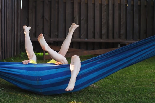 happy kids relaxing in a hammock outdoor. children's feet barefoot. Holidays vacation photo