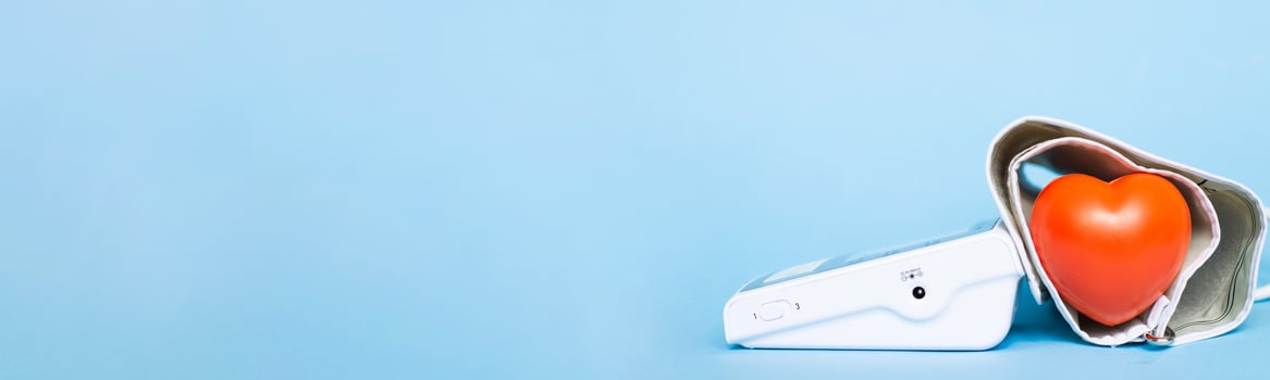 Red heart and white electronic tonometer isolated on a blue background photo