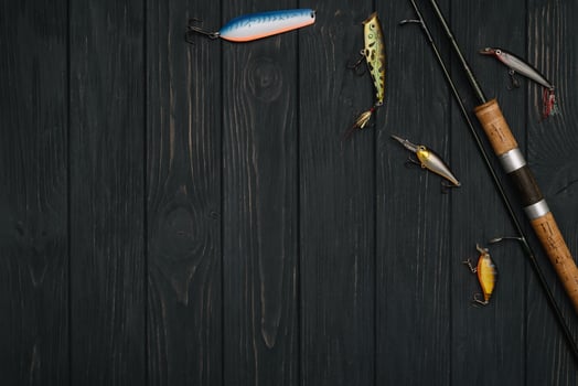Fishing tackle - fishing spinning, hooks and lures on darken wooden background. Top view photo