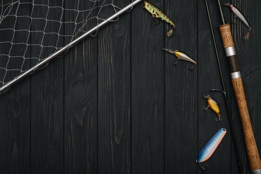 Fishing tackle - fishing spinning, hooks and lures on darken wooden background. Top view photo