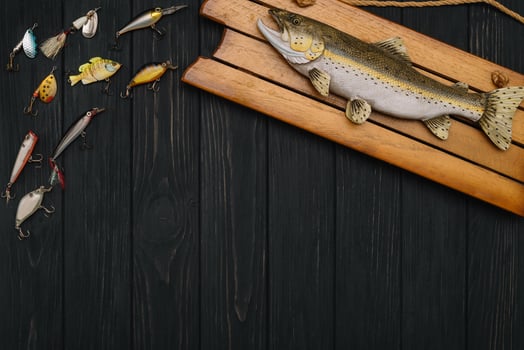 Fishing tackle - fishing spinning, hooks and lures on darken wooden background. Top view photo