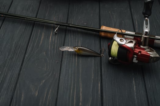 Fishing tackle - fishing spinning, hooks and lures on darken wooden background. Top view photo
