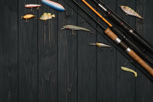 Fishing tackle - fishing spinning, hooks and lures on darken wooden background. Top view photo